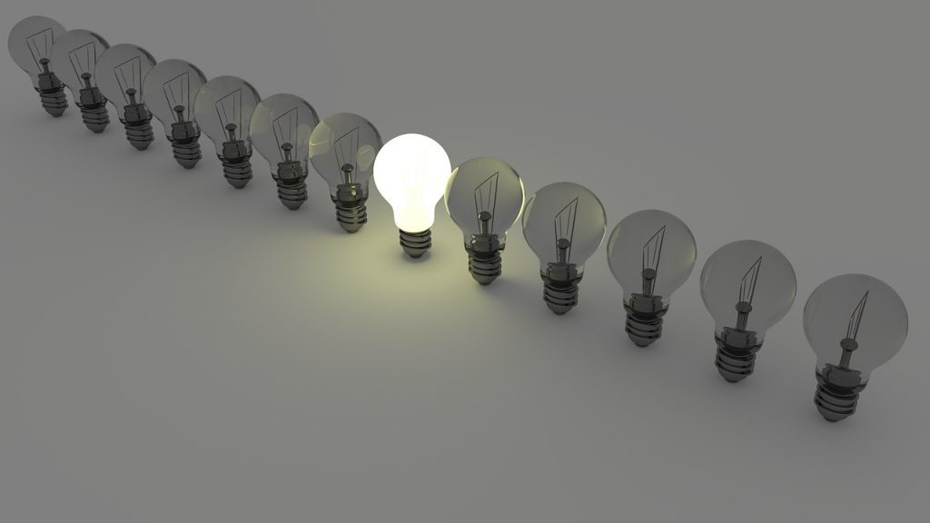 one lit lightbulb in a row of dark bulbs