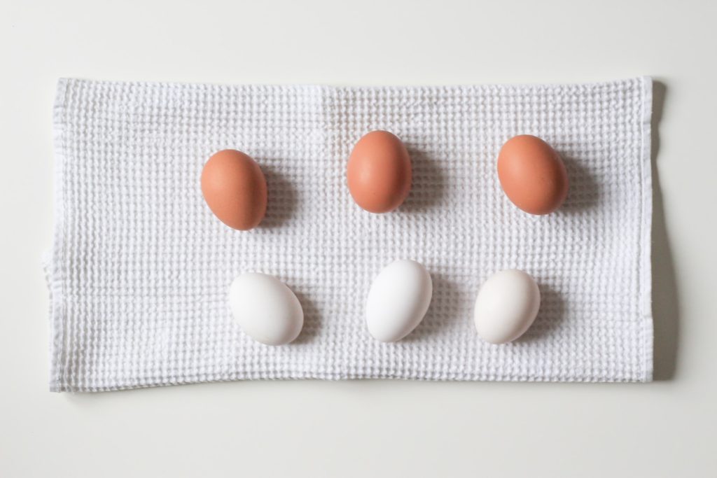 comparison - six white and brown eggs on white towel