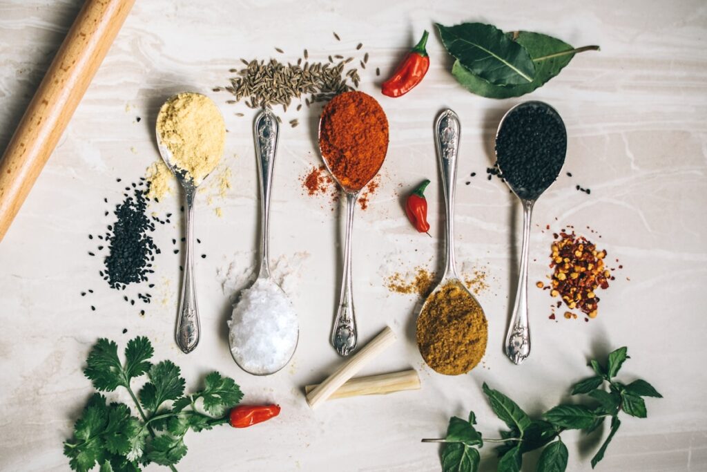 five gray spoons filled with assorted-color powders near chilli